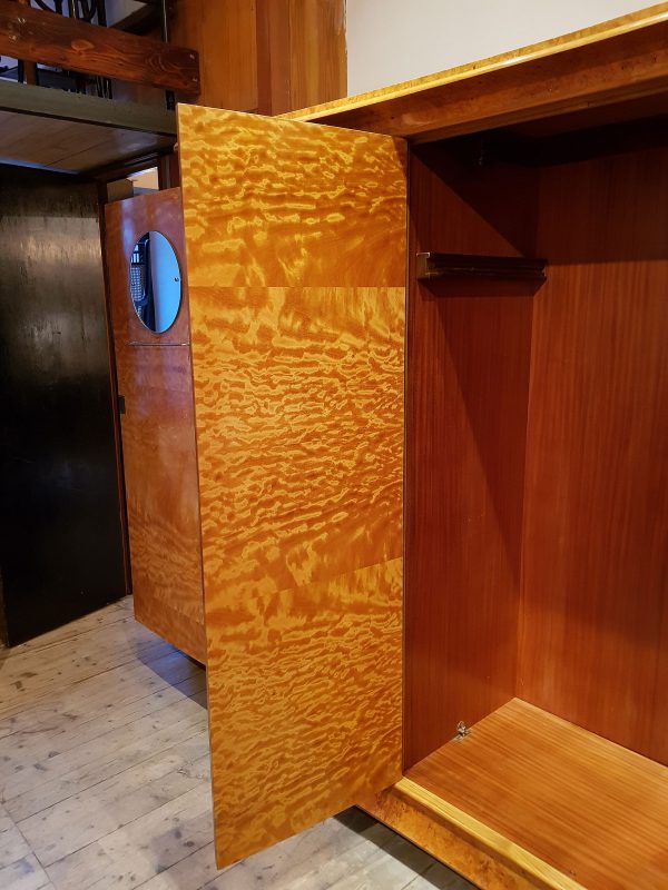 A fabulous Swiss four door wardrobe with burr walnut veneer exterior and sumptuous satin wood veneer interior. The front of the wardrobe is a gentle inward curve between two columns in an Egyptian deco style with central decorated column carved at top and bottom.